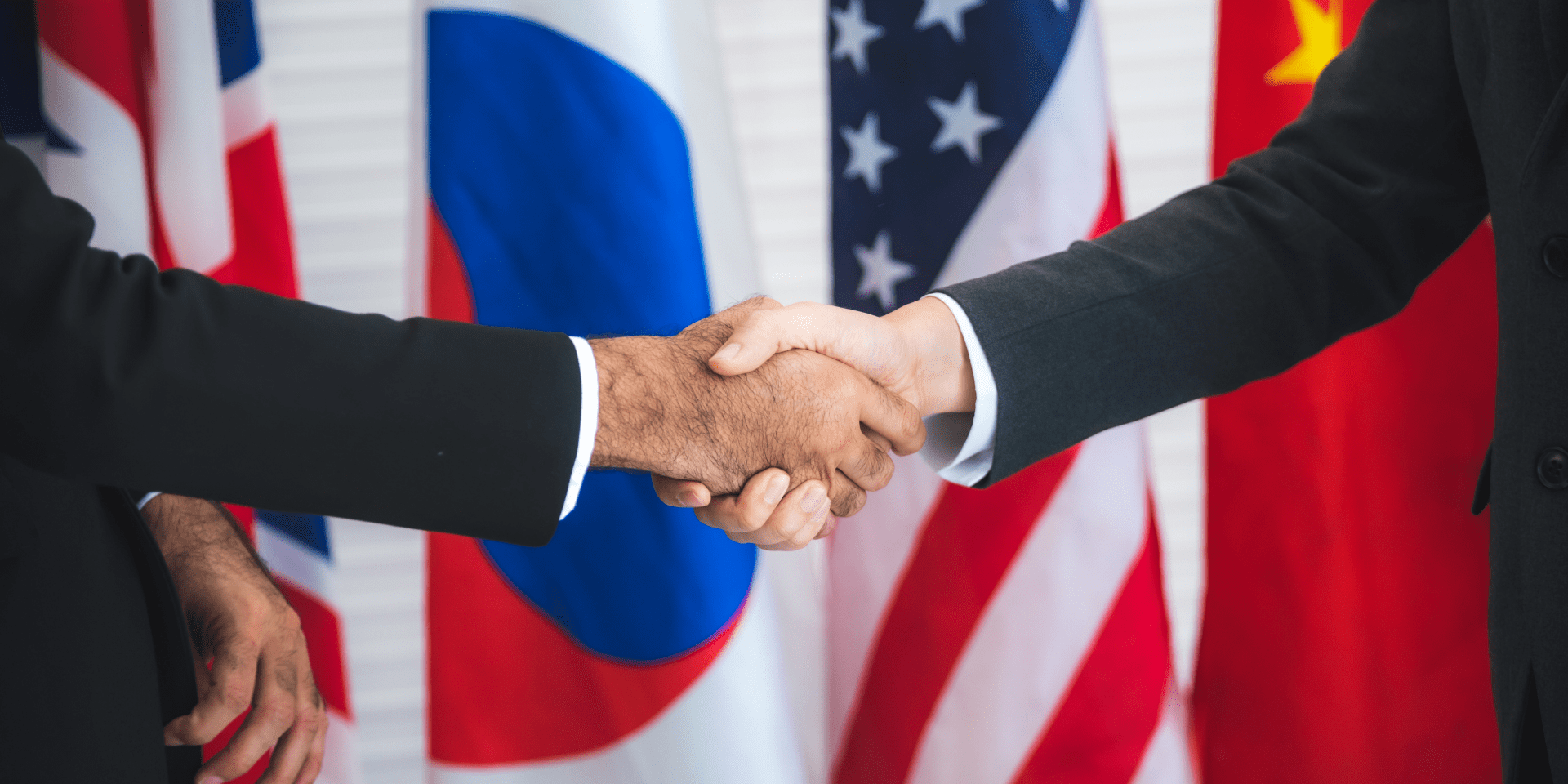 an image of two people shaking hands in front of various country flags