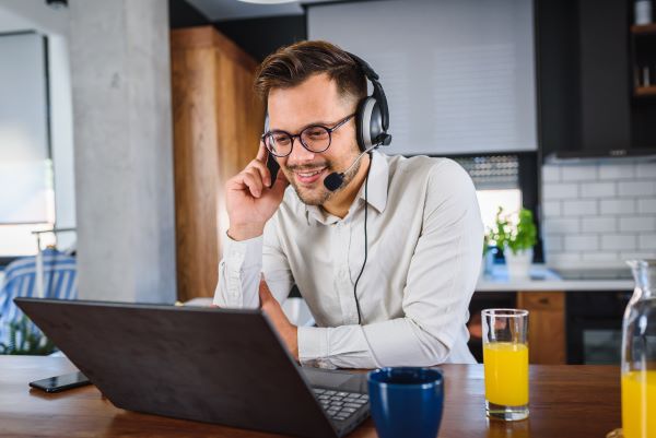 Young man working from home, sitting in front of laptop computer having meeting over internet.