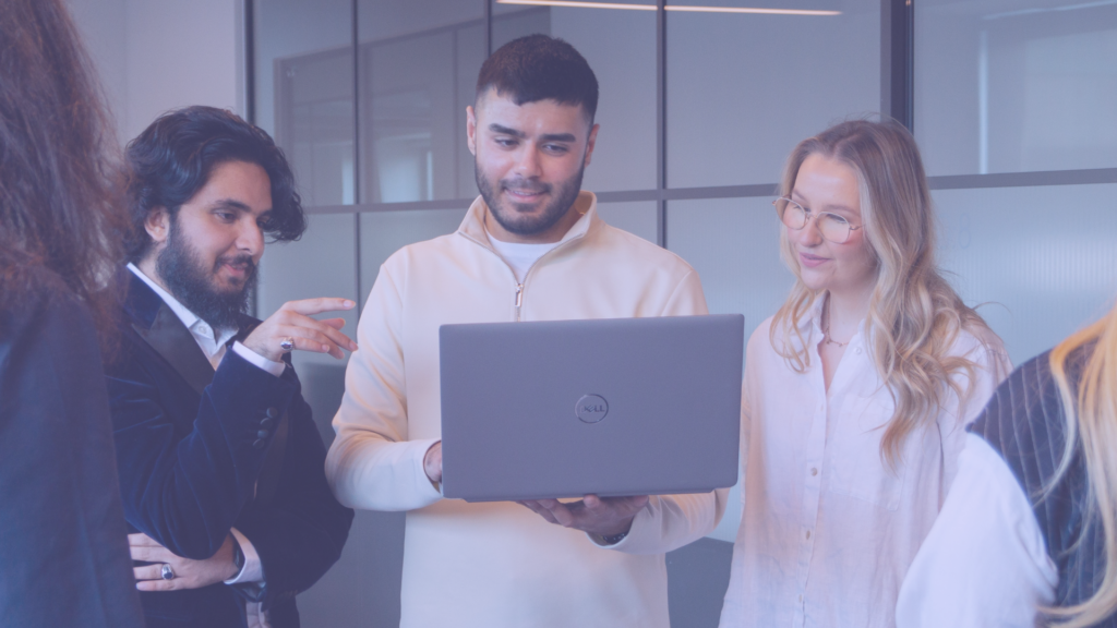 Three people looking at a laptop and collaborating.