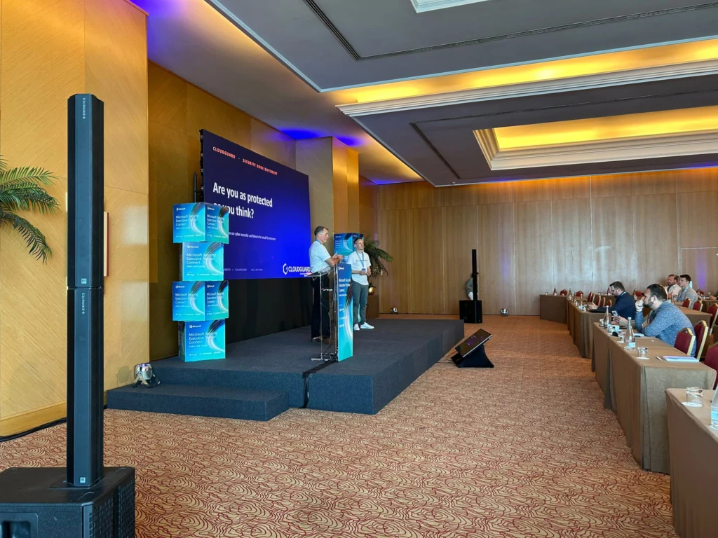 Two men on stage presenting in front of people at conference